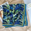 Detail van zijden sjaal met blauwe bloemen en groene rand op satijnen textuur - 68x68cm / Blauw