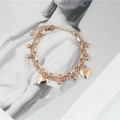 Roségoldenes doppellagiges Kettenarmband mit Herzanhängern und Perlen auf Zeitschriftenhintergrund - Roségold