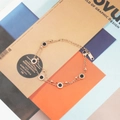 Elegante bracciale doppio strato in oro rosa con ciondoli neri su sfondo di rivista grafica - Oro rosa