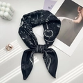 Detail of silk scarf with black heart and key prints paired with pearls and candles - White