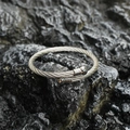 Sleek stainless steel braided cable open bangle with polished ball ends on rock - Steel Color
