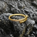 Polished gold twisted cable stainless steel cuff bracelet on a dark stone background - Gold Style