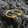 Golden titanium steel braided wolf head cuff bracelet shown on dark rock background - Gold
