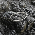 Minimalist silver oval titanium steel bangle with a polished mirror finish on dark rock - Shiny Steel Tone (Large)