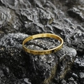 Polished gold stainless steel oval bangle on natural rock background in a minimalist style - Shiny Gold (Large)
