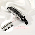 Detail of banana hair clip with large pearls and sparkling rhinestones on black resin - 11.5cmx5cm