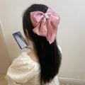 Pink satin bow hair clip with pearls and rhinestones shown on model from back - Pink
