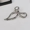 Dettaglio di un fermaglio per capelli in metallo argento lucido con design a fiocco - Stile Fiocco C-2
