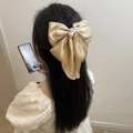 Champagne gold satin bow hair clip with a large pearl and rhinestone center on long hair - Khaki
