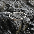 Oval silver stainless steel bangle with a brushed matte finish on a dark stone background - Brushed Steel Tone (Large)