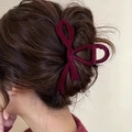 Macro detail of burgundy velvet bow hair claw clip styled on elegant brunette hair - Red