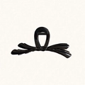 Pinza per capelli nera lucida a forma di fiocco con design elegante su sfondo beige - Nero