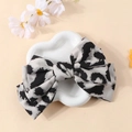 Close-up of leopard print bow hair clip on heart-shaped porcelain tray with daisy - White Leopard
