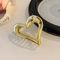 Detail einer goldenen Haarklammer aus Metall mit einem ausgehöhlten Herzdesign - Gold