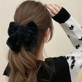 Lazo de pelo negro afelpado mostrado en el cabello de una modelo con estilo elegante - Negro