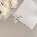 Detailopname van een zilveren haarspeld met strik en gepolijste afwerking op wit papier - Zilver