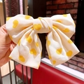 Fiocco per capelli crema con cuori gialli tenuto in mano per un look dolce - Beige Cuore Giallo (Nastro Corto)