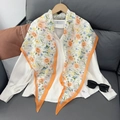Close-up van zijden sjaal met bloemenprint en oranje rand op wit overhemd - Oranje