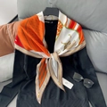 Detail van een oranje zijden sjaal met paardenthema over een zwarte trui met V-hals - Rood