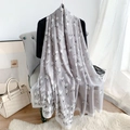Detalle de bufanda de seda gris con estampados de tulipanes blancos en un sofá - Gris