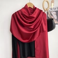 Detalle de un chal largo de seda rojo oscuro con acabado brillante en percha de madera - Burdeos