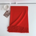 Detailed view of heavy red cashmere-feel scarf with elegant fringe trim on a white table - 185x70cm / Bright Red