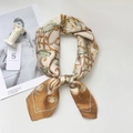 Detail of elegant floral silk scarf with rose patterns and brand tag on marble decor - Brown