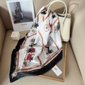 Classic silk scarf with carriage pattern draped on a cream leather handbag - Black