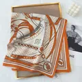 Detailed view of square scarf with equestrian chain prints on a golden frame display - Orange