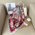 Elegante zijden sjaal van 70 cm met rode bloemen gedrapeerd op een beige handtas met decors - Rood