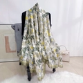 Détail d'une écharpe en satin de soie à fleurs jaunes avec bordure vert olive sur chaise - Vert