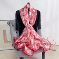 Texture détaillée d'un foulard soyeux à fleurs drapé sur un fauteuil chic en velours gris - Rose
