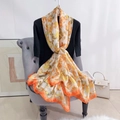 Détail d'un foulard en satin de soie orange à fleurs posé sur un canapé chic - Orange