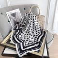 Foulard chic à pois noir et blanc noué élégamment sur un sac à main beige luxueux - Blanc