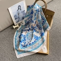 Elegant floral print silk square scarf styled on a luxury leather handbag - Blue