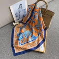 Close-up of orange floral silk scarf tied on a beige handbag with a fashion magazine - Orange