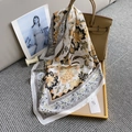 Detailed close-up of a vintage square silk scarf with floral paisley patterns on a satin texture - Yellow