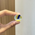 Nahaufnahme der kleinen gelb-blau-weißen Volleyball-Haarklammer zeigt die Miniaturgröße - Volleyball