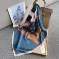Detalle de un pañuelo de seda de lujo con patrones de cachemira sobre un bolso beige - 70x70cm / Azul