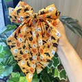 Detail view of large Halloween bow clip with orange pumpkin, ghost and bat print patterns - Orange Yellow