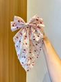Detail of oversized Christmas bow clip featuring festive Santa Claus and gold star prints - White