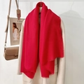Elegant solid red scarf with fringe edges draped over a beige coat for a warm winter look - Red