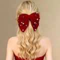 Détail d'un nœud en velours rouge avec strass brillants sur cheveux blonds ondulés - Rouge