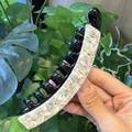 Close-up of black acetate banana hair clip with white marble inlay and dense grip teeth - White Marble Pattern