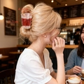 Detailed size view of drink cup hair claw clip on model in a cozy cafe setting - Coffee