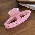 Pink translucent matte hair claw clip with hollow triangular design on a wooden table - Pink