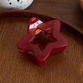 Pinza para el pelo estrella rojo oscuro con muelle dorado sobre fondo de madera - Rojo
