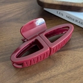Large dark red hair claw clip with glossy finish and geometric design on wooden table - Red