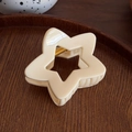Pince à cheveux étoile blanc crème avec finition brillante posée sur un plateau en bois - Beige