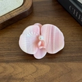 Elegant pink acetate orchid hair clip with a central pearl on a wooden background - Pink